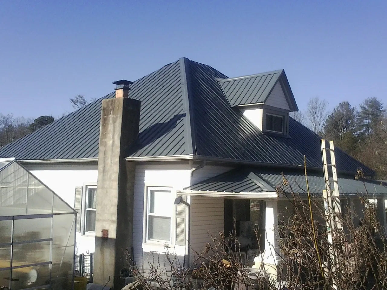 Dark blue standing seam metal roof on a white farmhouse with dormer — Slate & Tile Roof Repair by Roofing Brothers in Bradfordwoods