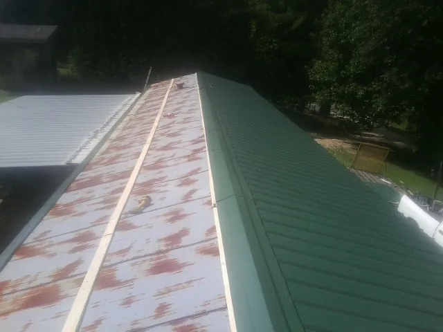 Old rusted panels beside newly installed green metal roofing — Wind Damage Roof Repair by Roofing Brothers in Bradfordwoods