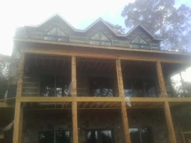Dormers and porch framing on a large log home under construction — Roof Coating work by our crew in Bradfordwoods