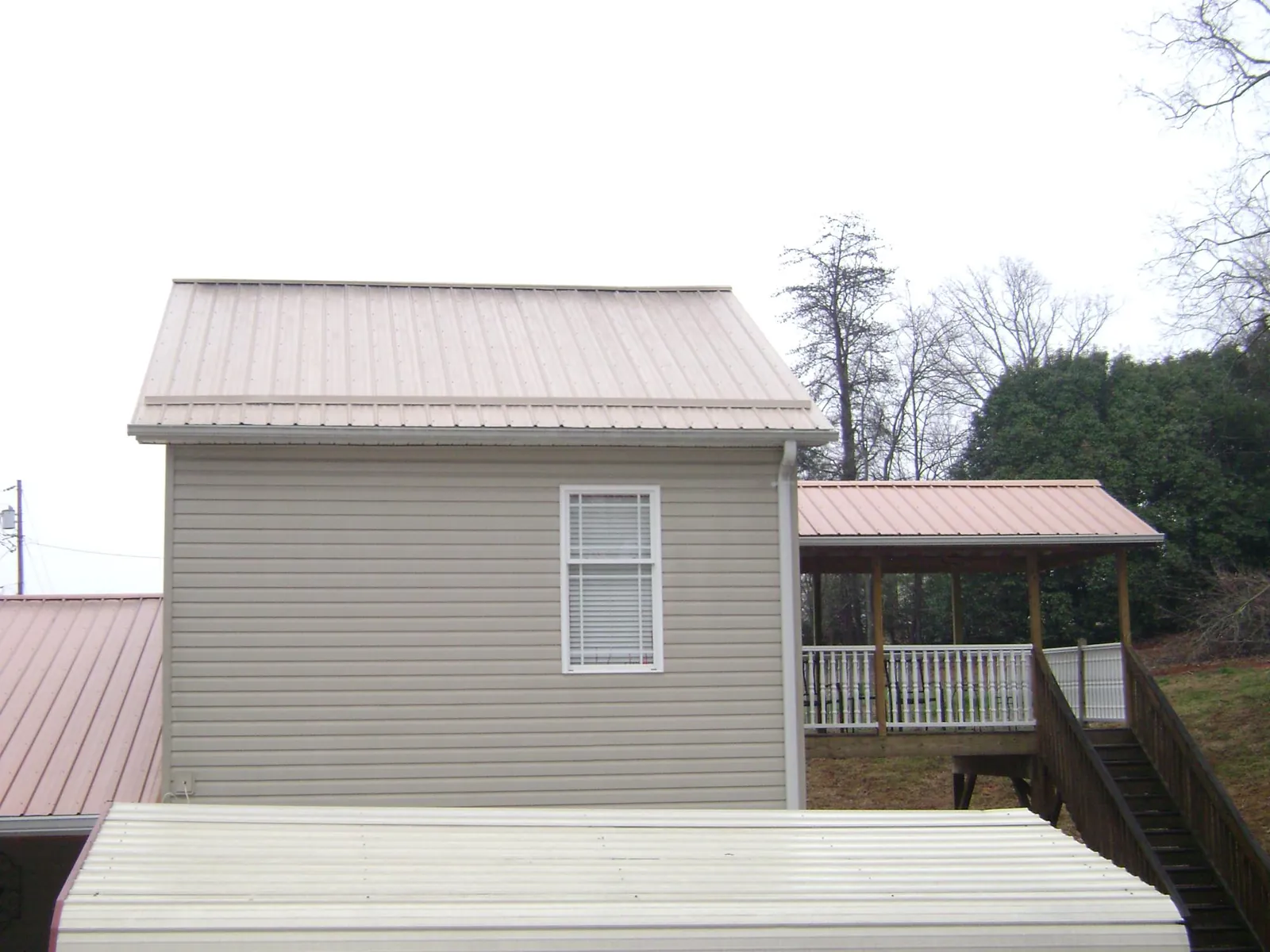 Tan metal roofs on a two story addition and attached porch, from a Roof Replacement job in Bradfordwoods