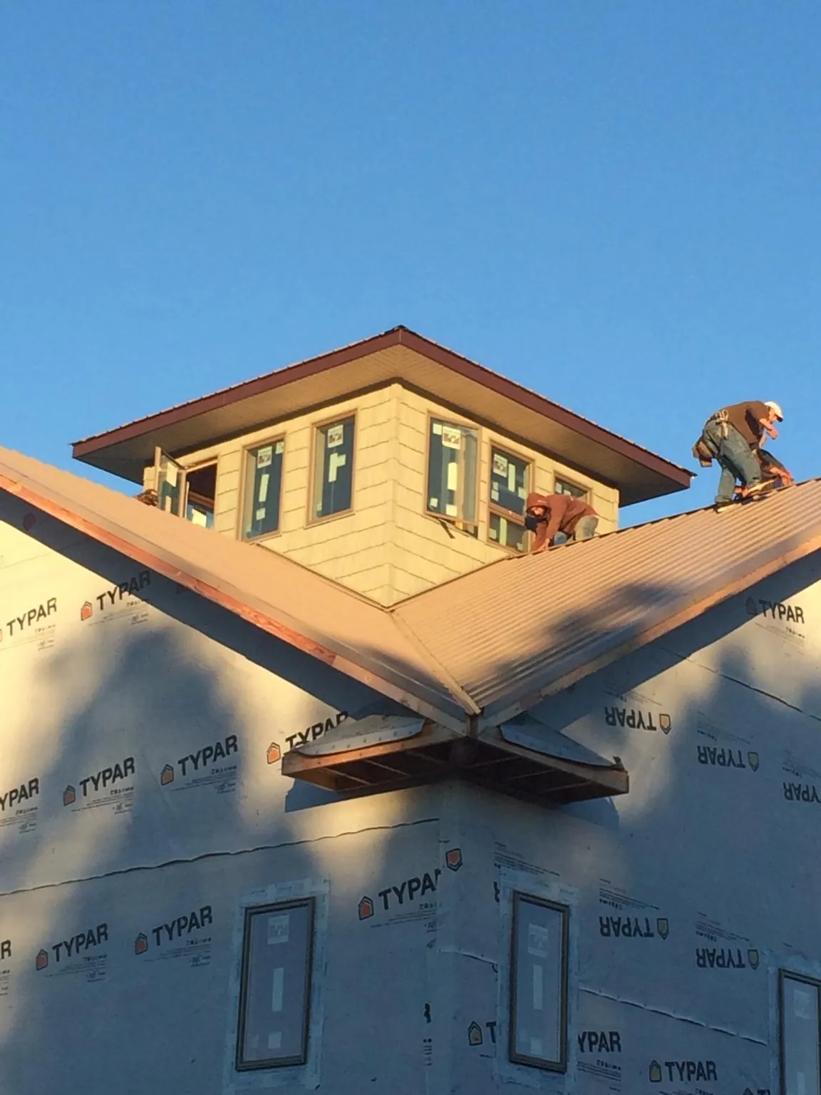 Roofers working around a rooftop cupola on a new metal roof at sunset — Roof Waterproofing in Bradfordwoods by Roofing Brothers